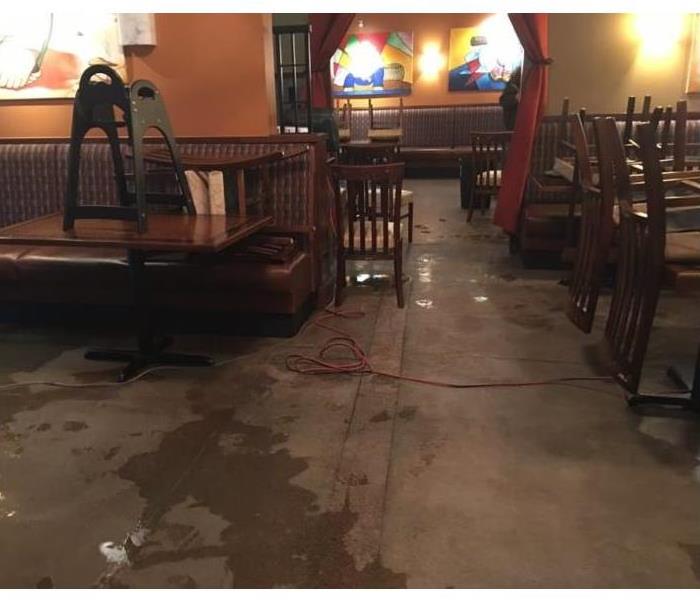 restaurant with flooding water damage to floors, tables, chairs, and walls 