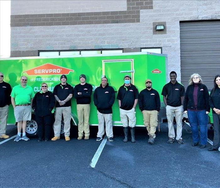 Group of SERVPRO team members standing in front of green trailer